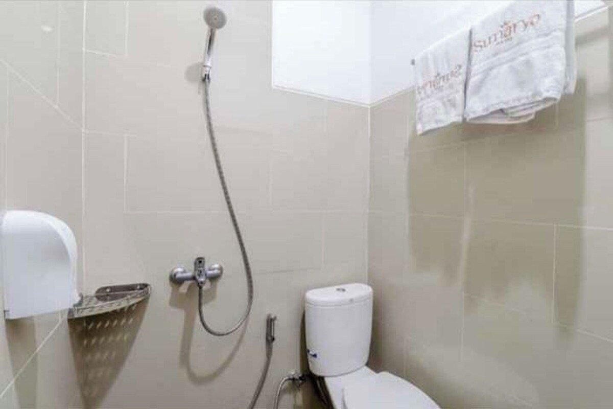 A bathroom with a shower, toilet, and a hand dryer.