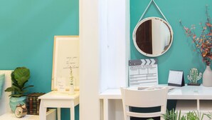 A teal-themed room with a white desk, a clapperboard, a mirror, a calendar, and a cactus plant. - The Art - Bong Gio House (Ho Chi Minh City)