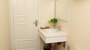 A bathroom with a white toilet, a sink, and a mirror above it. There is a towel rack with folded towels on it.