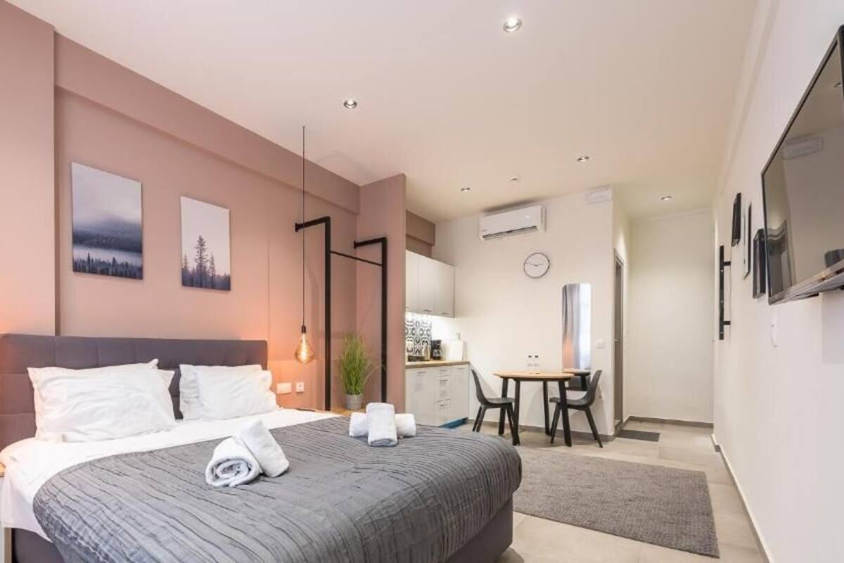 A modern hotel room with a large bed, bedside tables, a desk, and a TV.