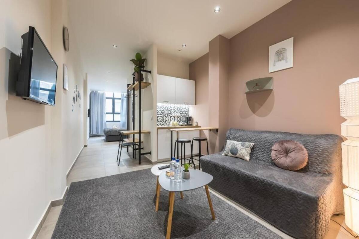 A modern living room with a grey sofa, a coffee table, and a TV mounted on the wall.