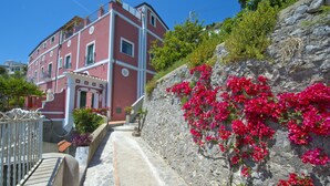 Un bâtiment rouge doté de balcons et d’un mur en pierre orné de fleurs roses.