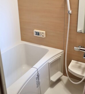A bathroom with a white bathtub, a small sink, and a shower. - Ooimazato Samurai House2 (Osaka)