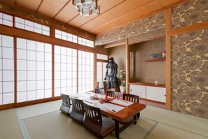 A traditional Japanese room with tatami flooring, a low table with cushions, and a statue. - Ooimazato Samurai House2 (Osaka)