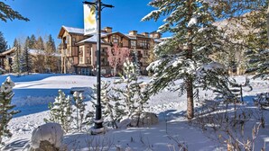 A snow-covered outdoor area with a building featuring a large banner. - Solitude Mountain Slopeside Ski Condo w/ Hot Tub! (Brighton)