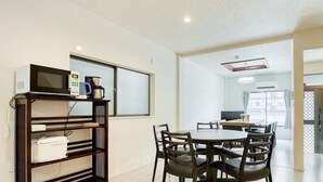 A modern hotel room with a dining area, a kitchenette, and a large window.