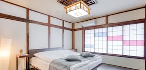 Quarto japonês tradicional com tatames, cama de madeira baixa e janela com tela shoji.