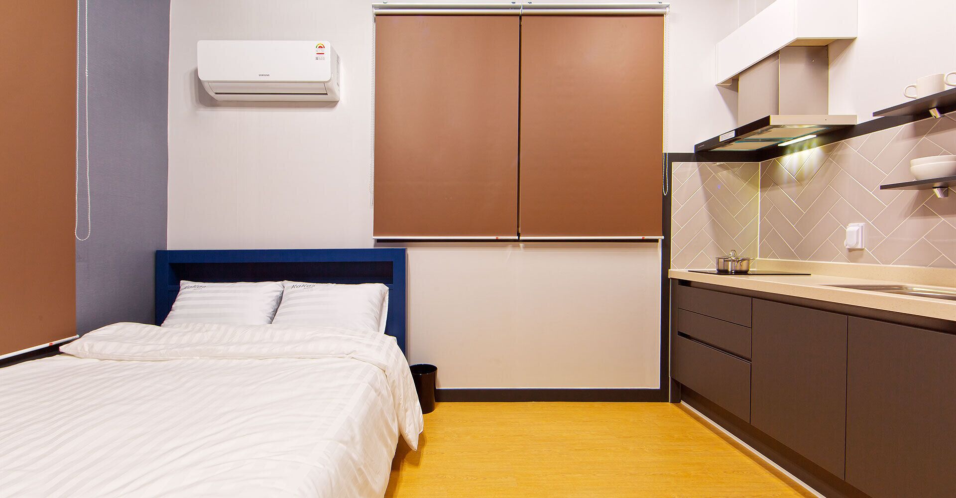 A hotel room with a bed, a kitchenette, and a wall-mounted air conditioner.