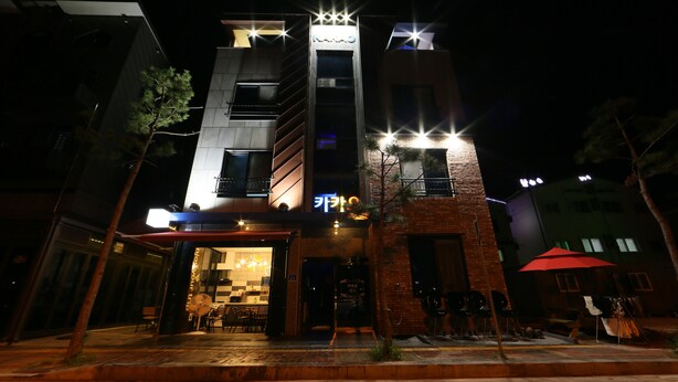 A modern building with a prominent entrance, a visible restaurant or café, and outdoor seating. - Kakao Pension (Boryeong)