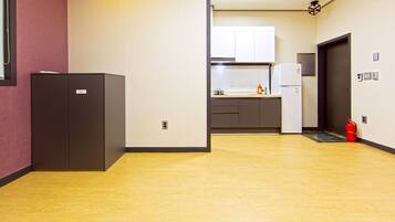 A hotel corridor with a wooden floor, a kitchenette area, and a fire extinguisher.