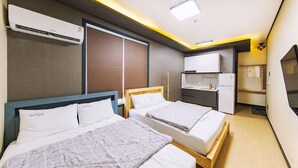 A hotel room with two beds, a kitchenette, a refrigerator, and an air conditioning unit. - Kakao Pension (Boryeong)