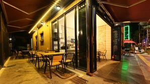 An outdoor dining area with tables and chairs, a fire extinguisher, and a neon sign. - Kakao Pension (Boryeong)