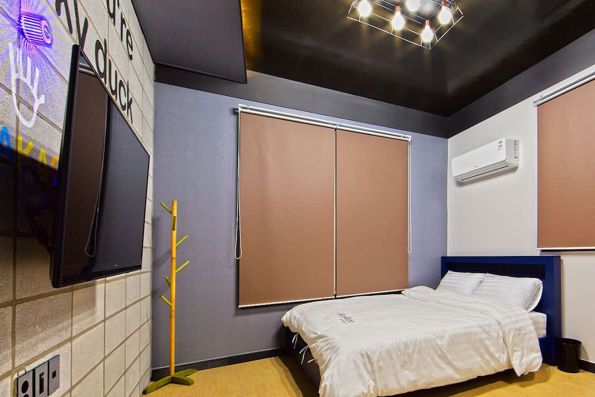 A bedroom with a bed, a wardrobe, a wall-mounted air conditioner, and a television.