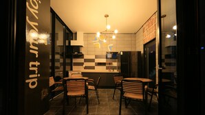 A modern restaurant with a checkered wall pattern, a central dining area with wooden chairs, and a visible kitchen counter. - Kakao Pension (Boryeong)