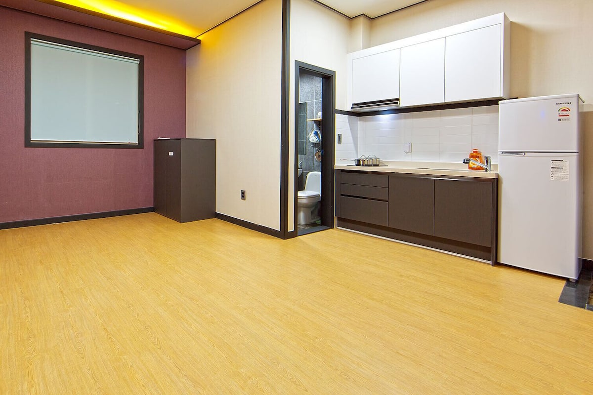A compact kitchen with a refrigerator, a sink, and cabinets.