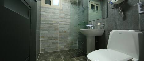 Une salle de bain avec douche, toilettes et lavabo.