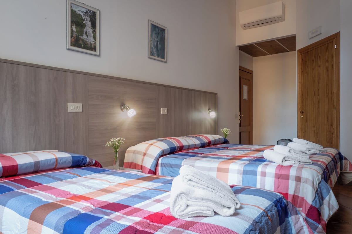 Ein Hotelzimmer mit zwei Betten, einem Holzkopfende, Wandleuchten und einer Tür.
