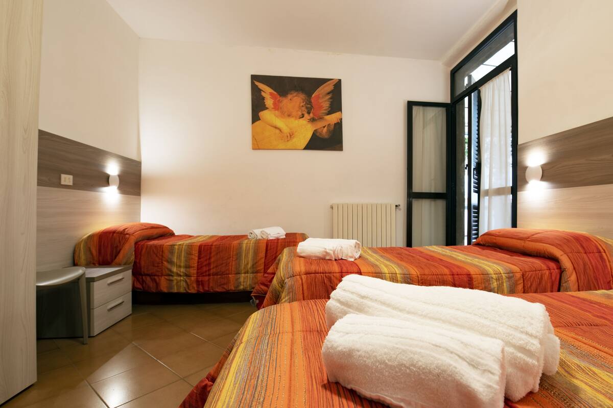 Ein Hotelzimmer mit zwei Betten, einem Nachttisch, einer Lampe und einem Bild an der Wand.