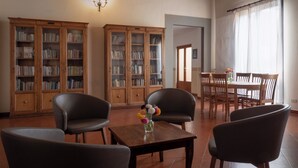 A room with two wooden bookshelves, a dining table with chairs, and a small table with a vase of flowers. - Foresteria Valdese di Firenze - Casa per Ferie (Florence)