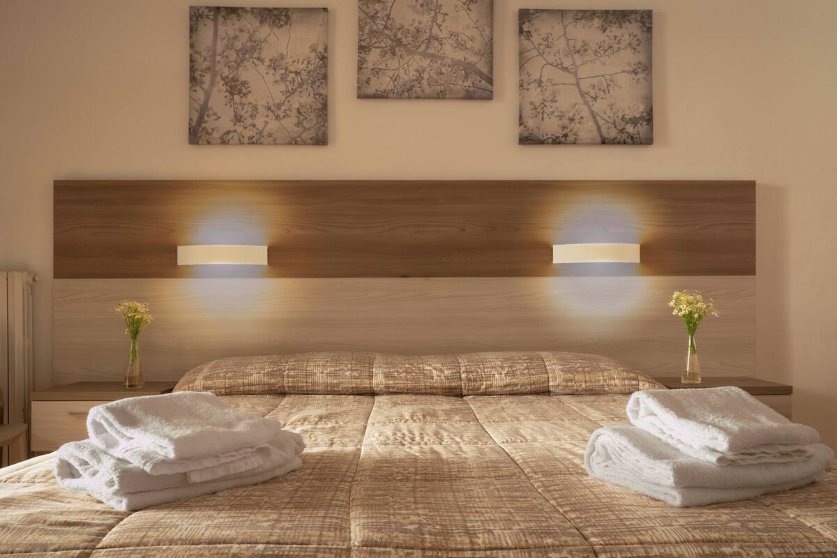 Ein Hotelzimmer mit einem großen Bett, zwei Nachttischen und drei Wandleuchten.