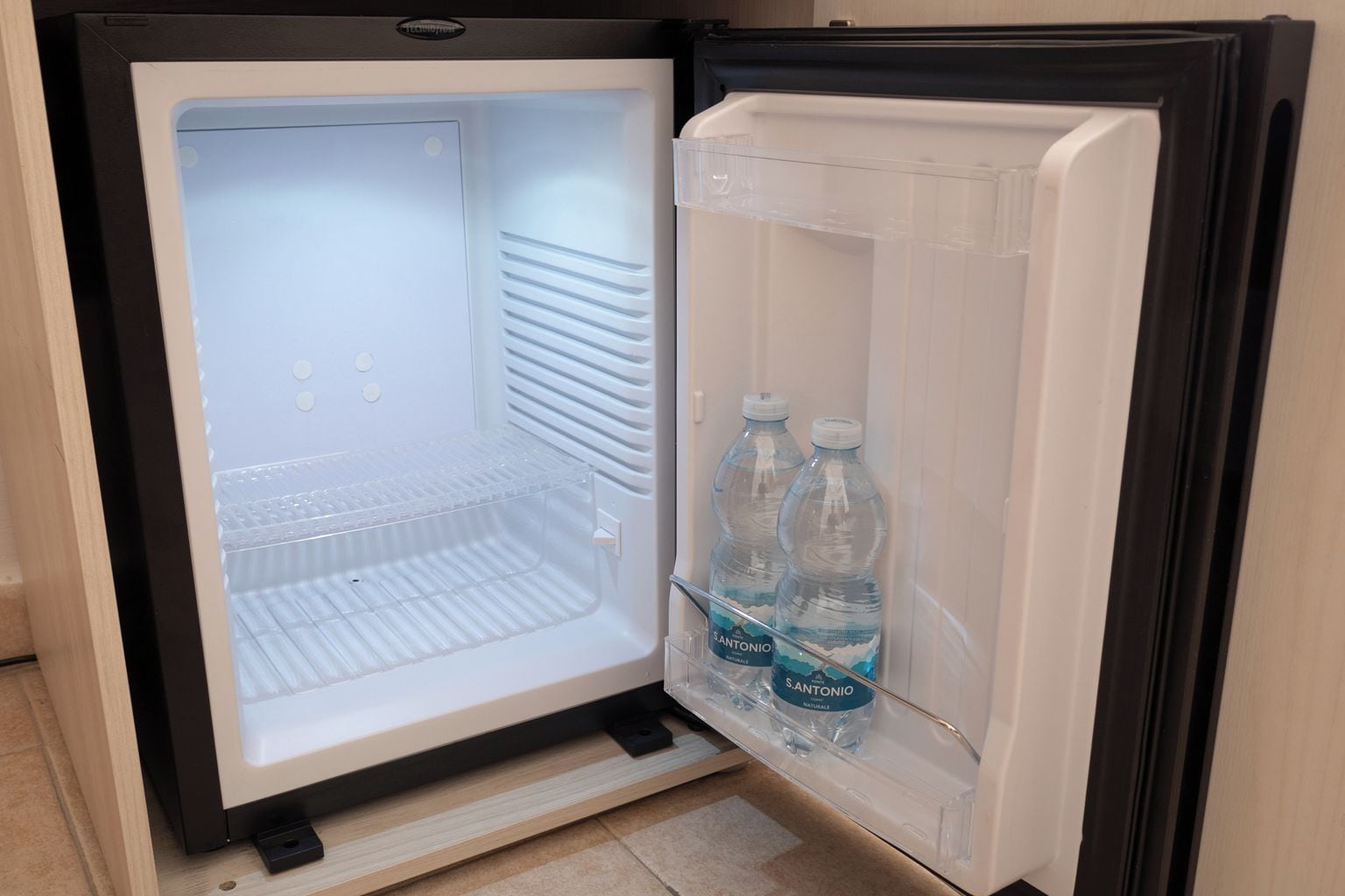 An open refrigerator with a water dispenser and a freezer compartment.