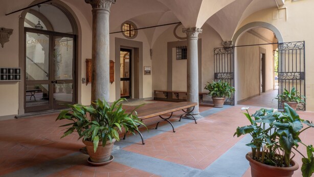 A covered courtyard with columns, a bench, and potted plants. - Foresteria Valdese di Firenze - Casa per Ferie (Florence)