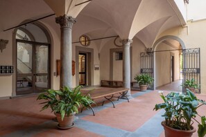 Une cour intérieure abritée, dotée de colonnes, d’un banc et de plantes en pot.