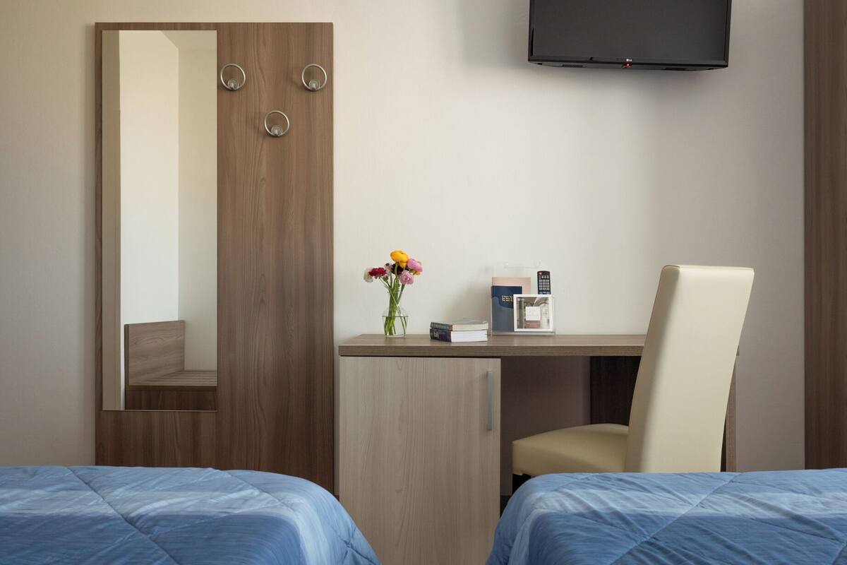 Ein Hotelzimmer mit einem Bett, einem Schreibtisch mit Stuhl, einem Fernseher und einem Spiegel.