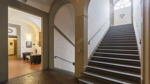 A staircase with a handrail, a fire alarm, and a door leading to a room with a fireplace. - Foresteria Valdese di Firenze - Casa per Ferie (Florence)