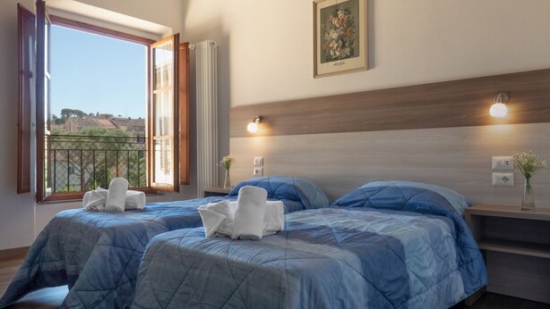 Ein Schlafzimmer mit zwei Betten, einem Fenster mit Blick, einer Wandleuchte und einem gerahmten Bild.