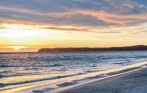 A beach with waves and a sunset.