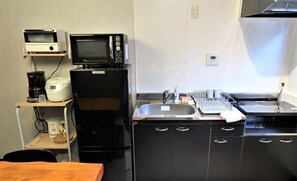 Une petite cuisine équipée d’un four à micro-ondes, d’une machine à café, d’un réfrigérateur, d’un évier et d’un égouttoir.