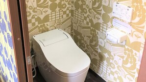 A bathroom with a toilet, a paper towel dispenser, and a wall-mounted electrical outlet. - Nakagawanisi Samurai House3 (Osaka)
