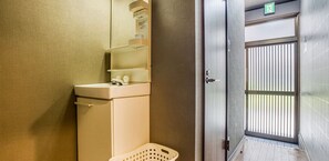 A bathroom with a sink, mirror, and a door leading to another room.