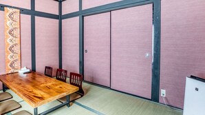 A conference room with a wooden table, four chairs, a patterned curtain, and sliding doors. - Ajiro Sakura House4 (Higashi-osaka)