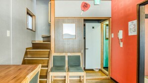 A hotel room with a wooden staircase, a small table, and two chairs. - Ajiro Sakura House4 (Higashi-osaka)