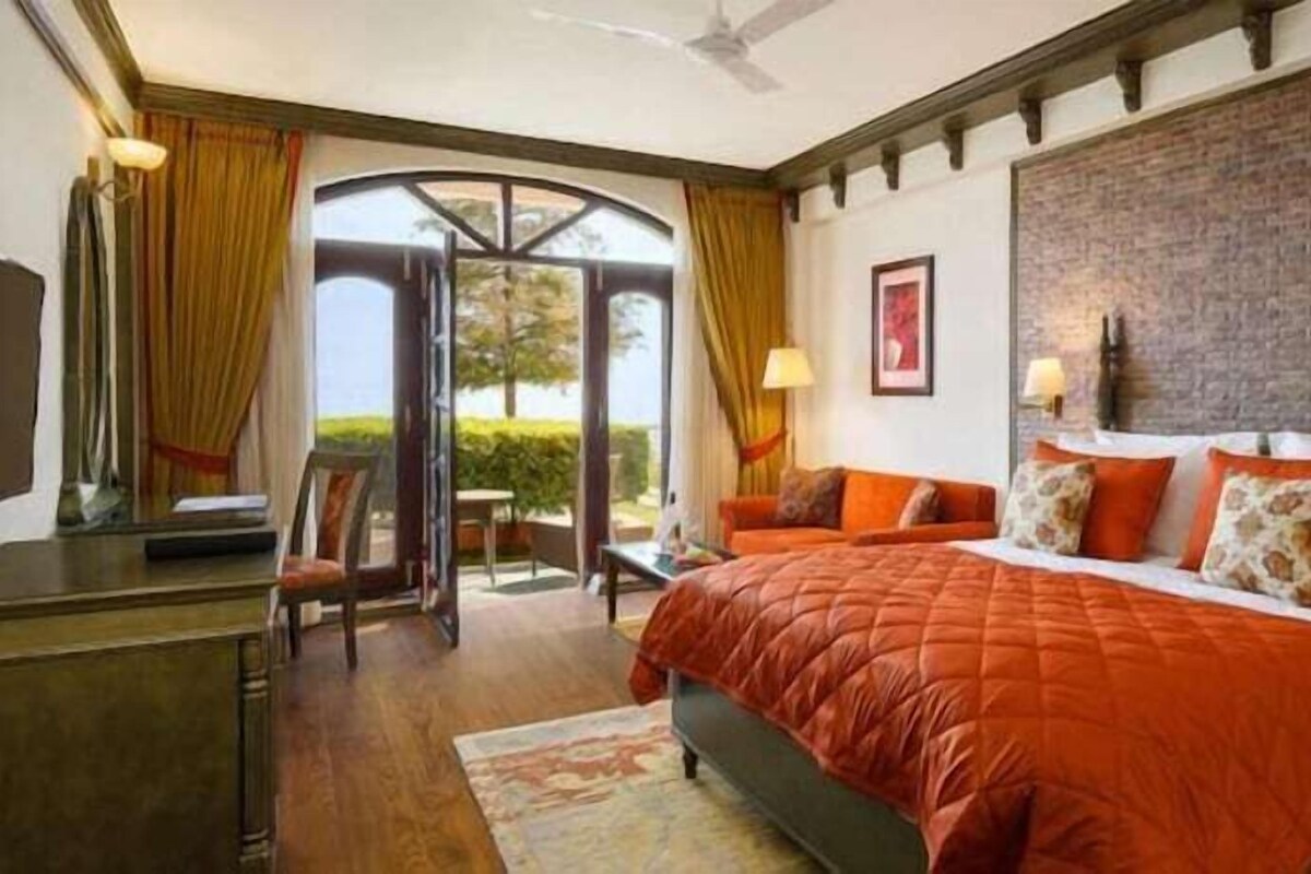 Een slaapkamer met een groot bed, een bureau, een stoel en een televisie.