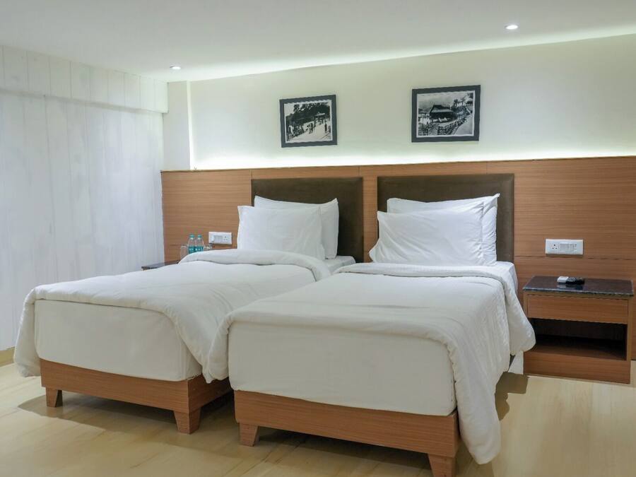 A double bed with a wooden headboard, two pillows, and a bedside table with a remote control.