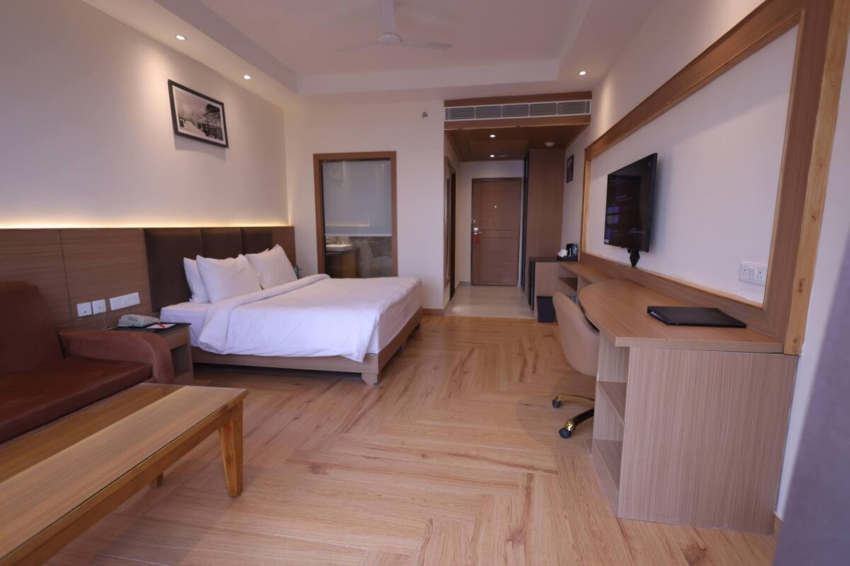 Une chambre d’hôtel avec un lit, un bureau, une télévision et un canapé.