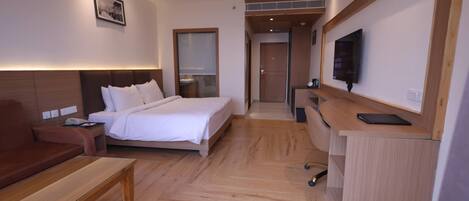 Una habitación de hotel con cama, escritorio, televisor y sofá.