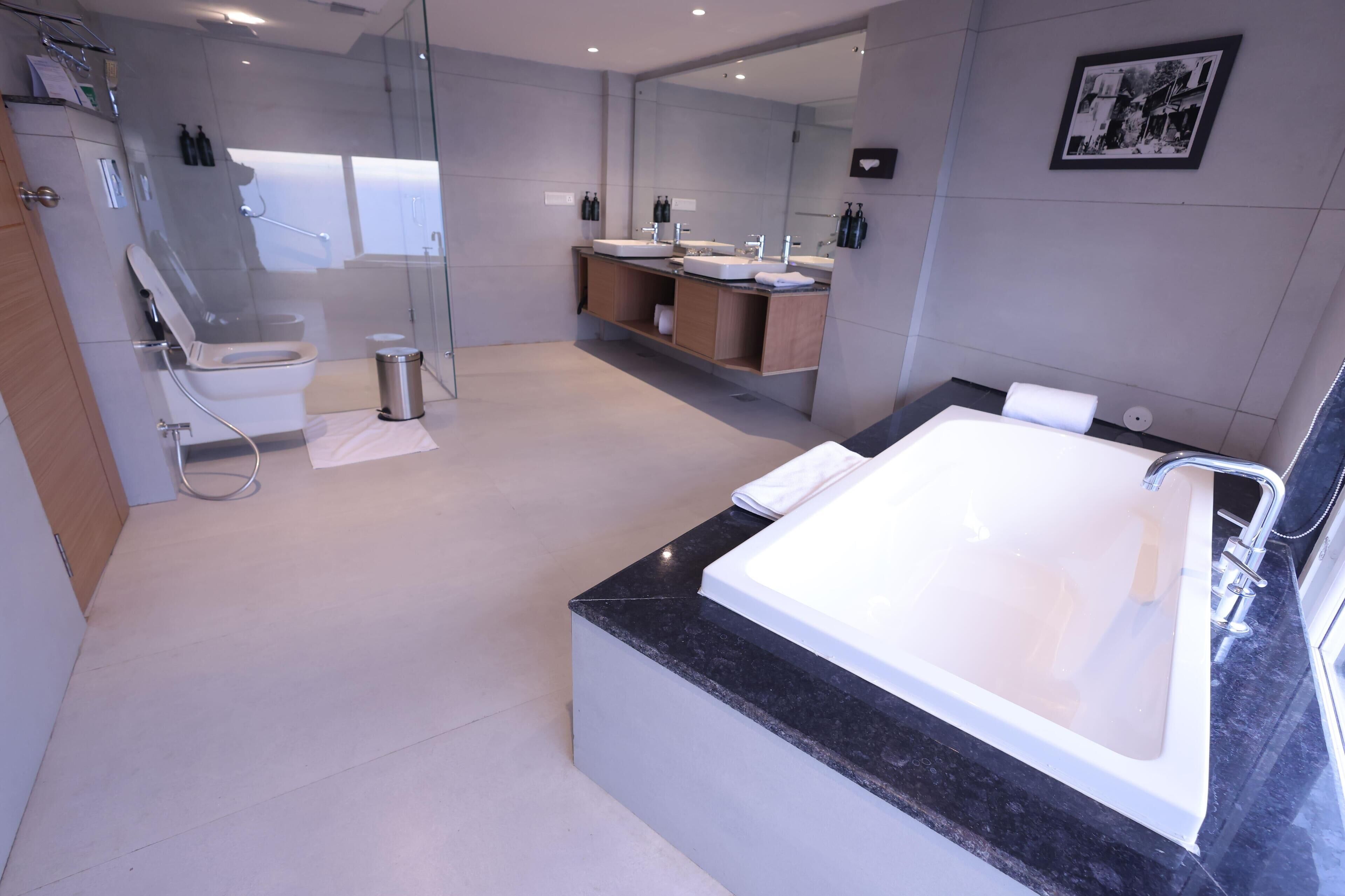A modern bathroom with a large bathtub, a glass-enclosed shower, and a vanity with a sink and mirror.