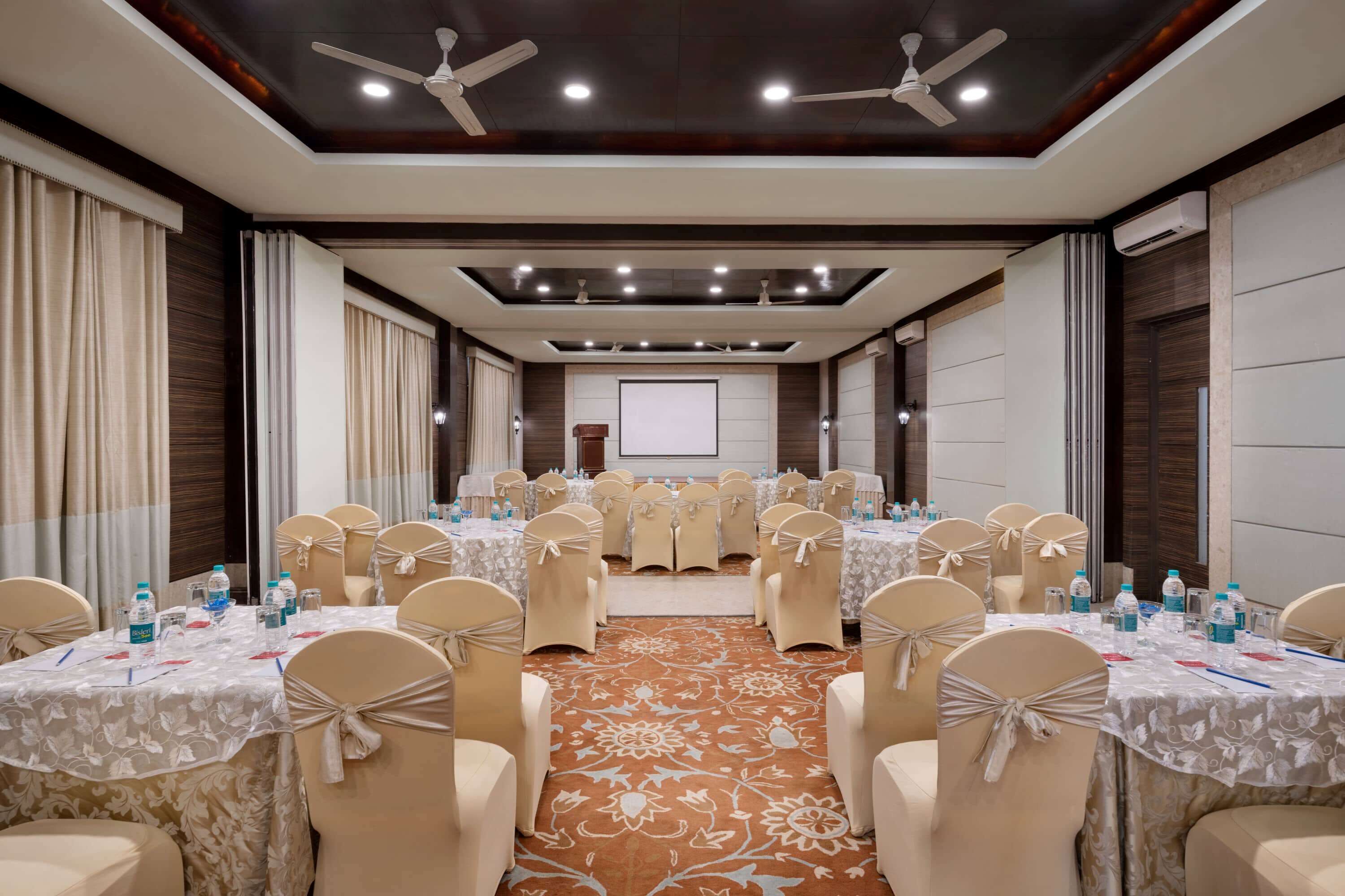 A conference room with tables set for a meeting, arranged in a U-shape with chairs.