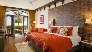 A hotel room with a large bed, a desk, a chair, and a TV. There is a brick wall and a window with curtains. - Ramada by Wyndham Mussoorie Mall Road (Dehradun)
