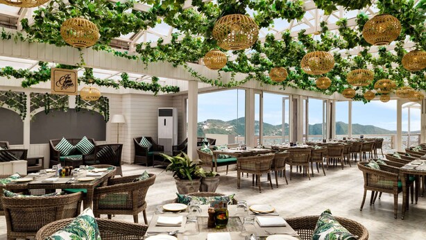 A spacious outdoor dining area with wicker furniture, green cushions, and hanging wicker lamps. - Ramada by Wyndham Mussoorie Mall Road (Dehradun)