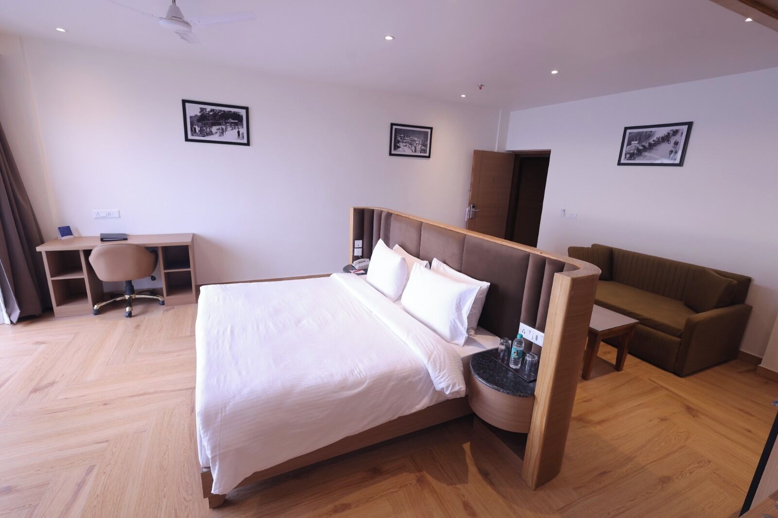 A hotel room with a large bed, a desk, a chair, and a sofa.