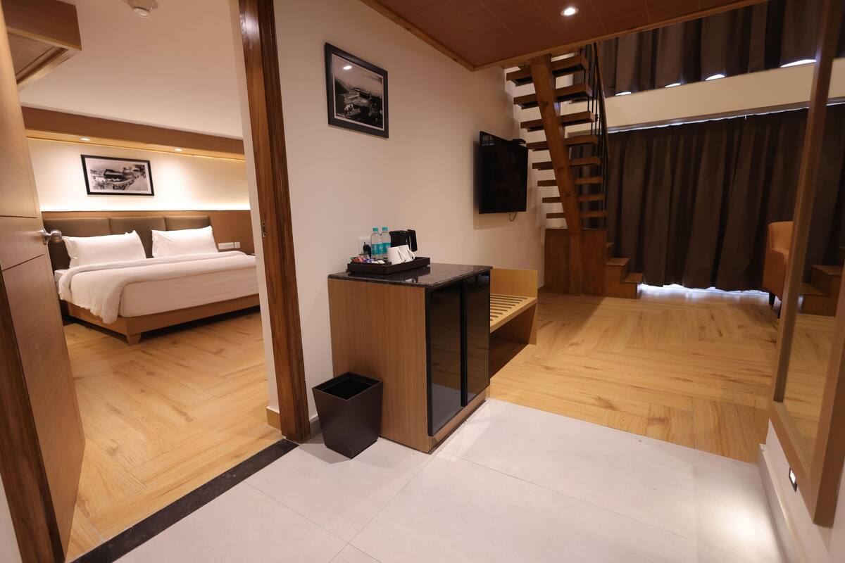 Une chambre d’hôtel avec un lit, un bureau, une poubelle, une télévision et un escalier.