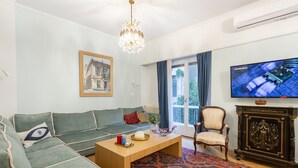 A living room with a sofa, a coffee table, a chair, a television, and a patterned rug. - A short walk to Syntagma and Plaka (Athens)