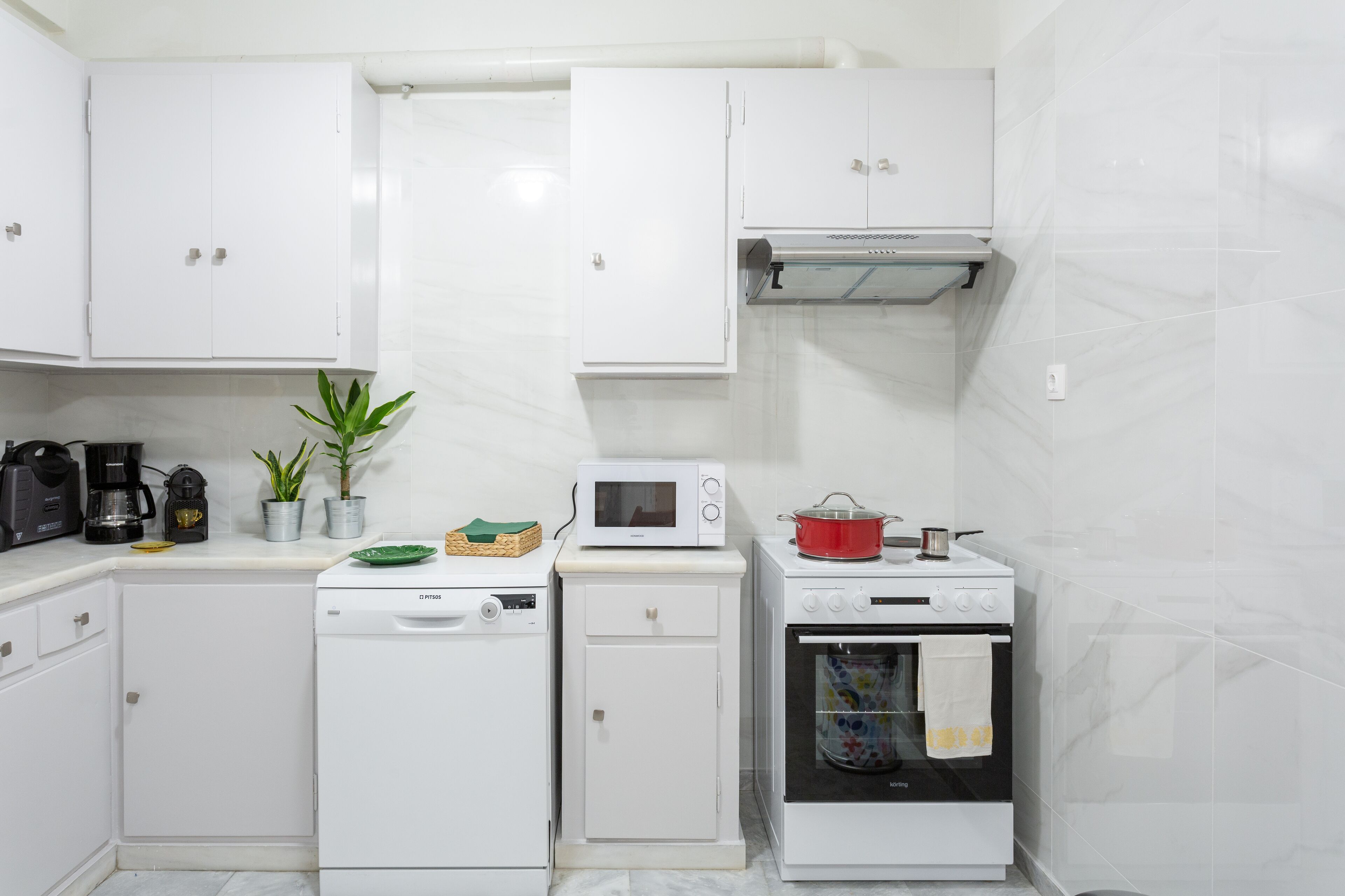 A compact kitchen with white cabinetry, a microwave, a dishwasher, and an oven.