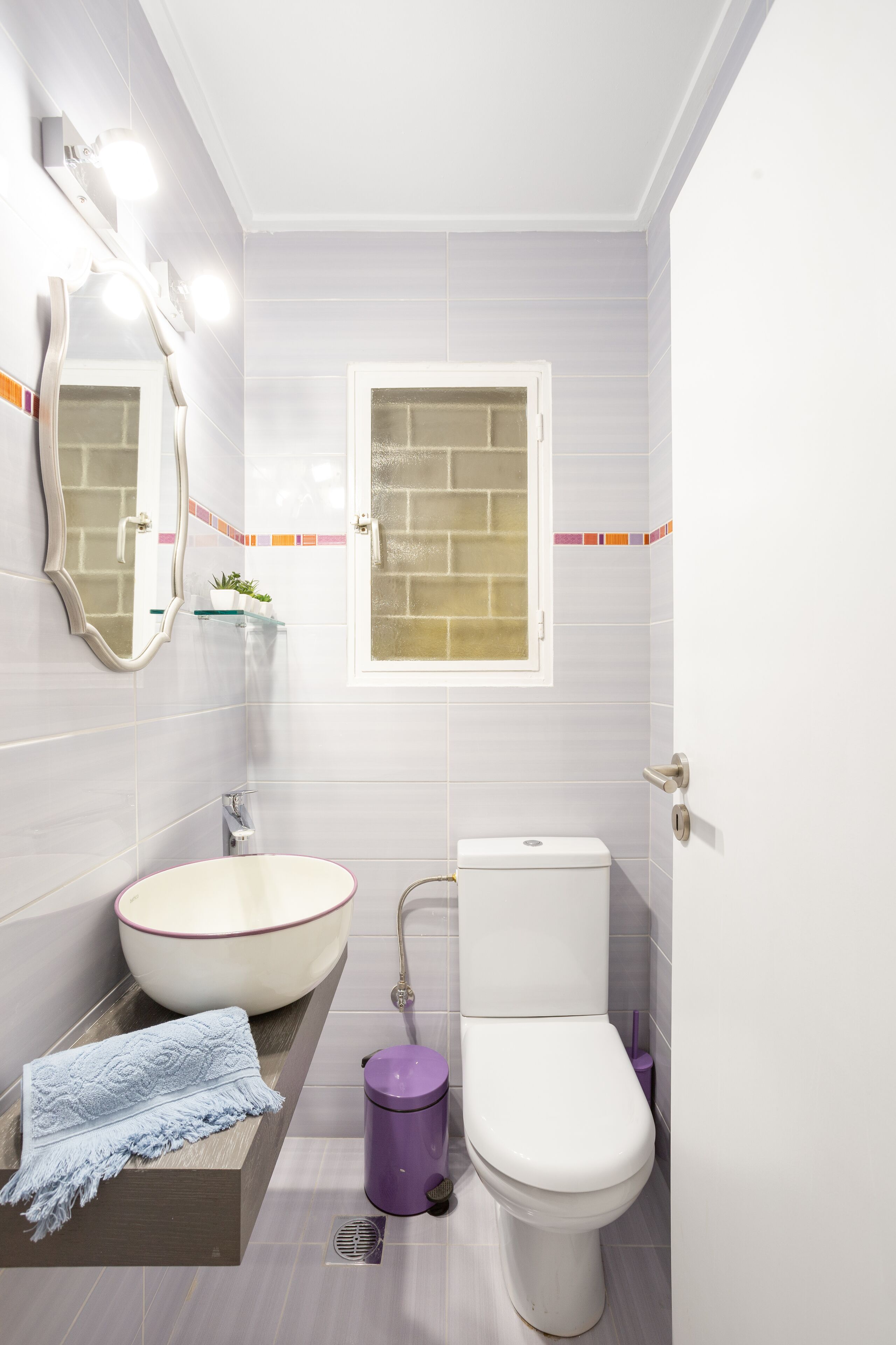 A bathroom with a white sink, a toilet, and a mirror with lights.