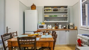 A compact kitchen with a dining table, chairs, a refrigerator, a microwave, and a coffee maker. - A Happy stay by Edem Beach (Palaio Faliro)